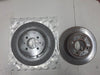 Two metal disc brake rotors on a white surface, one in a clear plastic bag.
